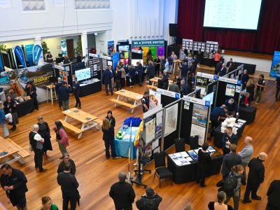 Bird’s-eye view of the Let’s Chat Ballarat 2026 Community Expo at Ballarat Civic Hall, showing community members speaking with Council staff, visiting information stalls and displays, and participating in activities throughout the exhibition space.