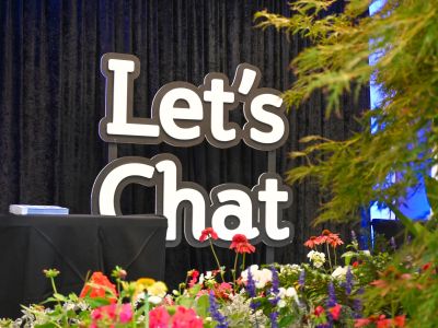 Let’s Chat Ballarat signage displayed among colourful flowers and greenery in the foyer of Ballarat Civic Hall during the Let’s Chat Ballarat 2026 Community Expo.